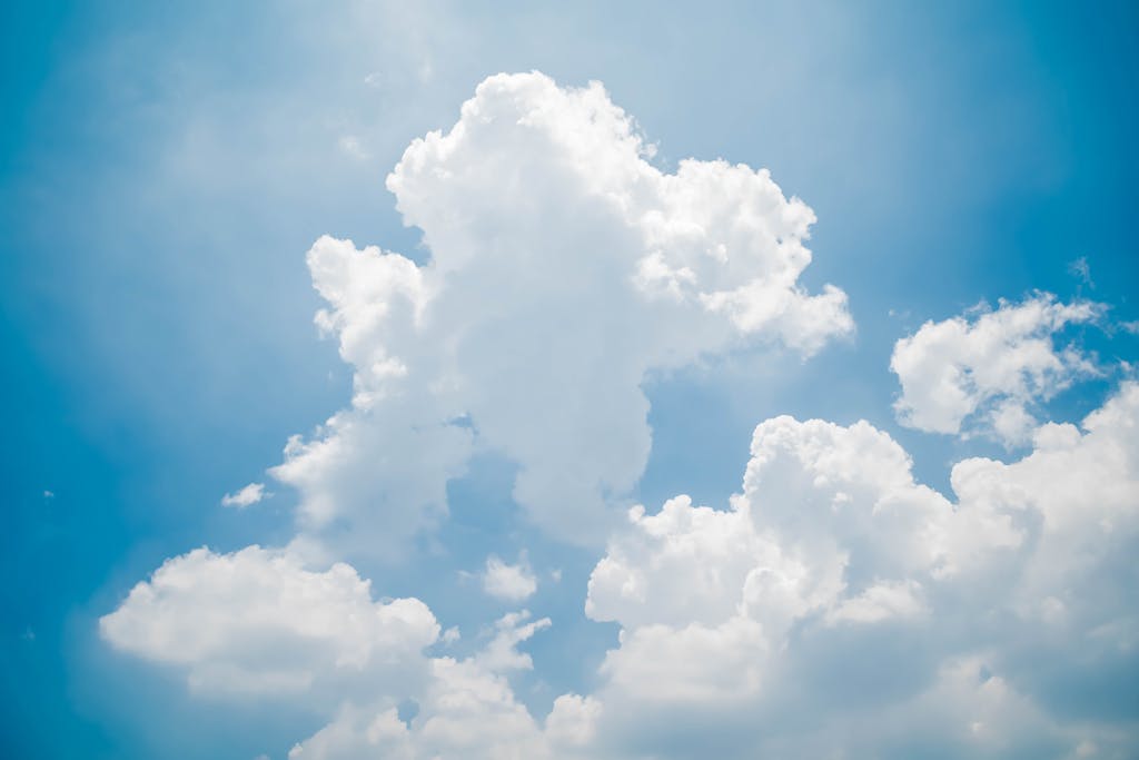 Bright white clouds against a clear blue sky on a sunny day, perfect for nature themes.
