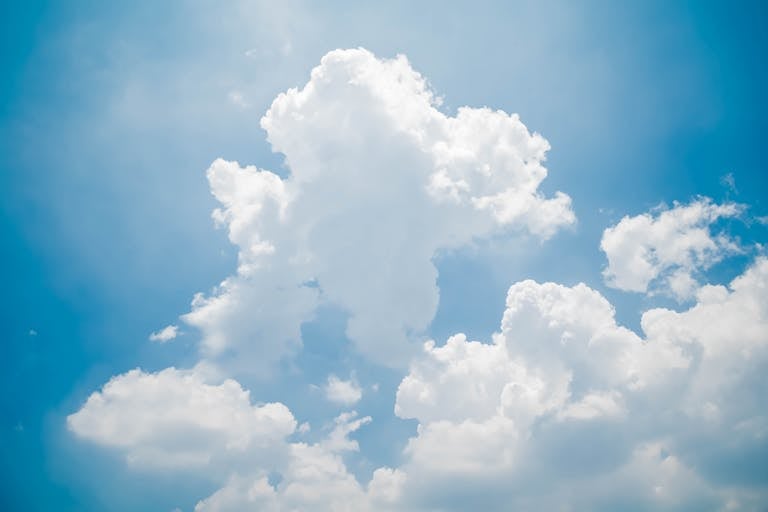 Bright white clouds against a clear blue sky on a sunny day, perfect for nature themes.