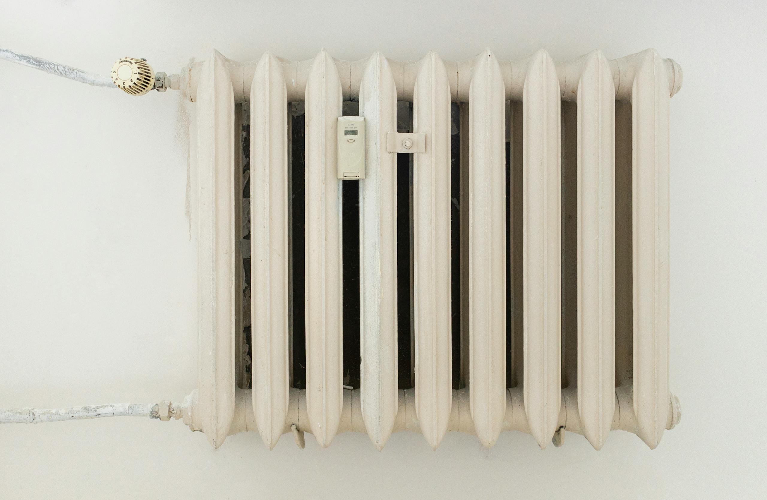 A classic white metal radiator on a plain wall, showcasing minimalist interior design.