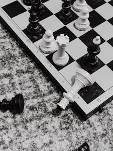 Close-up black and white chess pieces in strategic game position on board.
