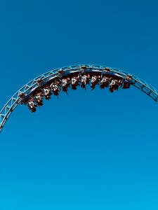 Experience the exhilaration of a roller coaster looping against a stunning blue sky.