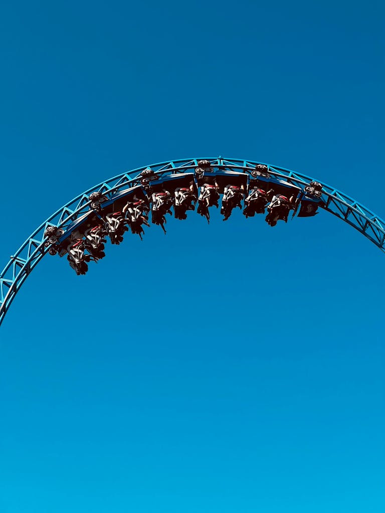 Experience the exhilaration of a roller coaster looping against a stunning blue sky.