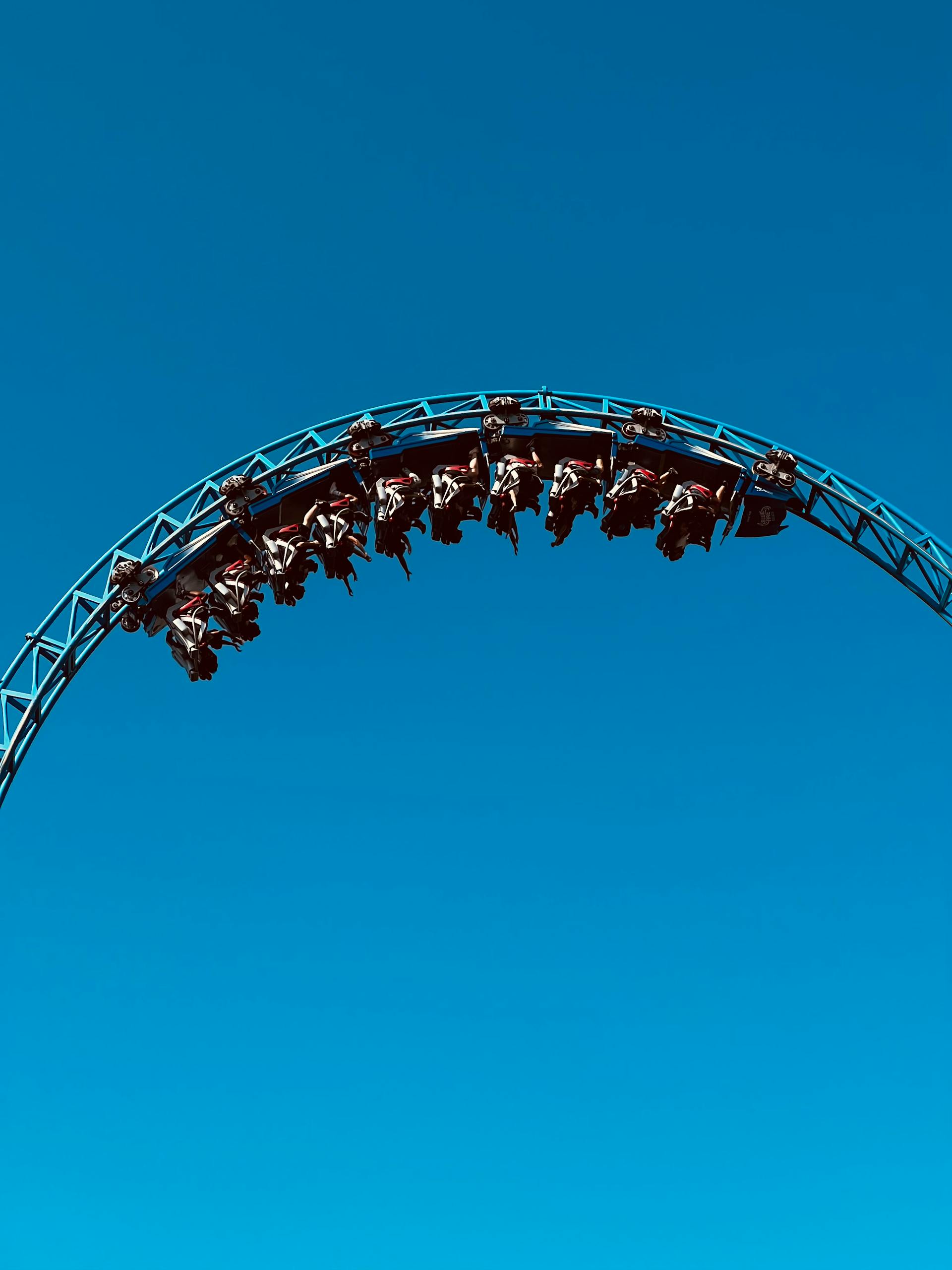 Experience the exhilaration of a roller coaster looping against a stunning blue sky.