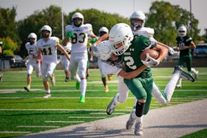 High school football players in intense action on the field during a game.