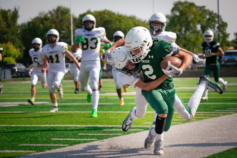 High school football players in intense action on the field during a game.