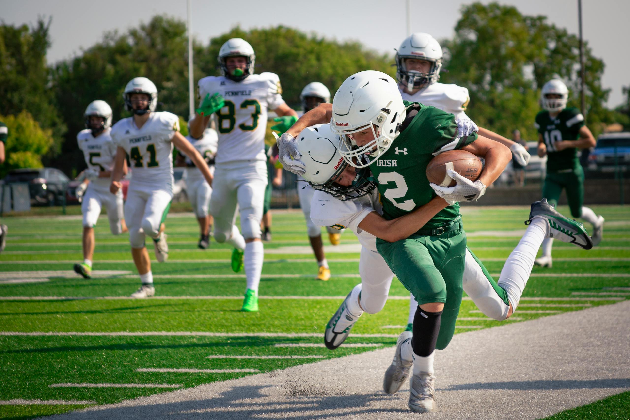 High school football players in intense action on the field during a game.