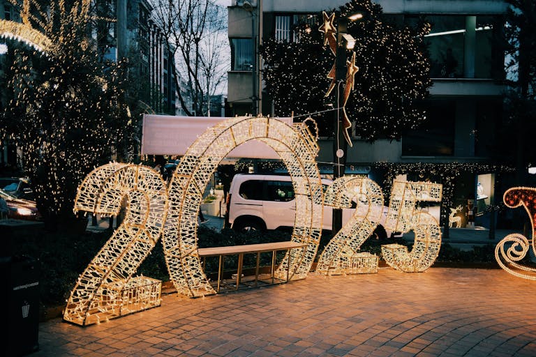 Illuminated 2025 sign on city street with decorative lights creating a festive atmosphere.