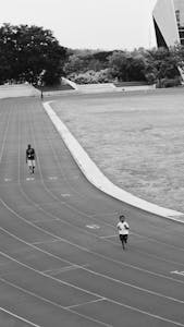 Monochrome image of children running on a track, showcasing athleticism and movement.