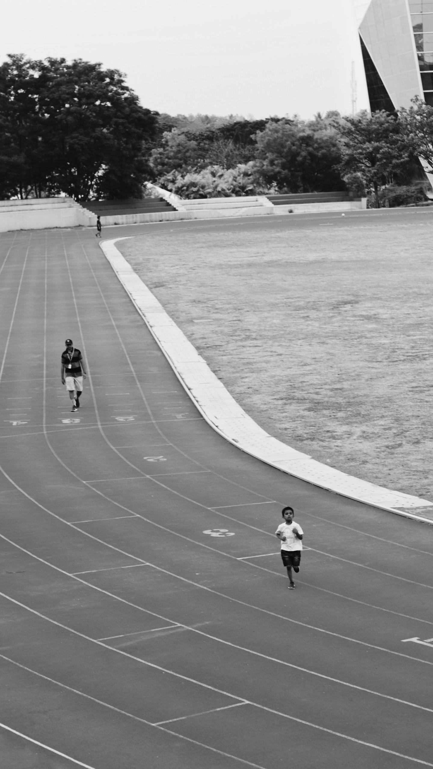 Monochrome image of children running on a track, showcasing athleticism and movement.