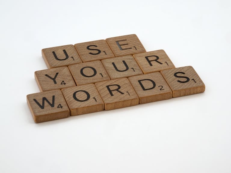 Wooden letter tiles spell 'USE YOUR WORDS' on a white background, promoting linguistic creativity.
