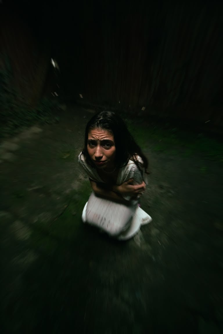 A woman appears frightened and uneasy in a dark, confined space.