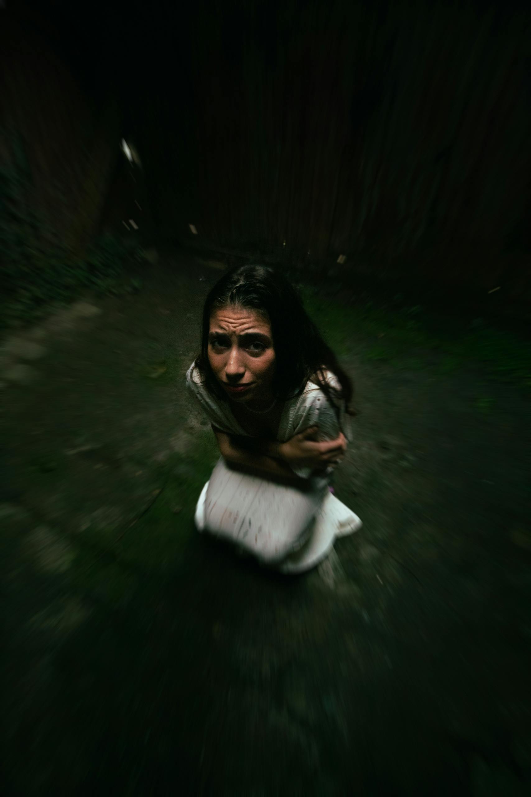 A woman appears frightened and uneasy in a dark, confined space.
