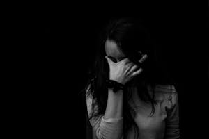 Intense black and white portrait capturing the emotion and introspection of a woman covering her face.